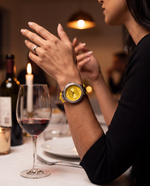 Clicöt Aphrodite 36mm women's watch in yellow and silver, worn on a woman's left wrist