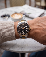 Clicöt Aurora 42mm unisex watch in black, gold and silver, worn on the left wrist