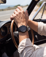 Clicöt Cronus 42mm watch in black on a man's left wrist, everyday lifestyle photo