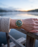Clicöt Eclipse 42mm unisex watch in green and gold, worn on the left wrist