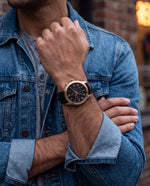 Close-up of the Clicöt Helios 42mm watch in black and gold on a man's left wrist