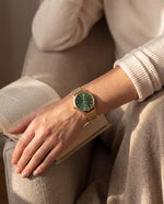Clicöt Hera 36mm women's watch in green and gold, worn on a woman's left wrist