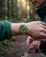 Clicöt Hera 36mm watch in green and gold on a woman's left wrist, everyday lifestyle photo