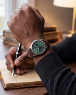 Close-up of the Clicöt Hermes 41mm watch in green, brown and silver on a man's left wrist