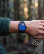 Clicöt Hypnos 36mm women's watch in black and blue, worn on a woman's left wrist
