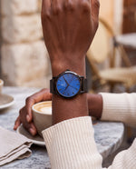 Clicöt Hypnos 36mm watch in black and blue on a woman's left wrist, everyday lifestyle photo