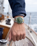 Clicöt Infinity 42mm watch in green, gold and silver on the left wrist, everyday lifestyle photo