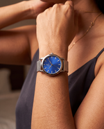 Clicöt Oceanus 36mm women's watch in blue and silver, worn on a woman's left wrist