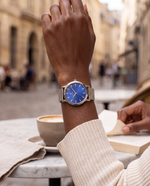Close-up of the Clicöt Oceanus 36mm watch in blue and silver on a woman's left wrist