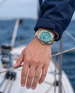 Clicöt Orion 42mm watch in teal, gold and silver on the left wrist, everyday lifestyle photo