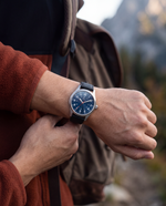 Clicöt Poseidon 41mm watch in navy and black on a man's left wrist, everyday lifestyle photo