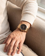 Clicöt Thor 42mm watch in black and gold on a man's left wrist, everyday lifestyle photo